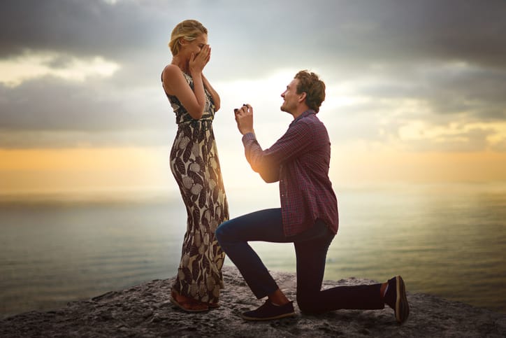 Shot of a young man proposing to his girlfriend at sunset