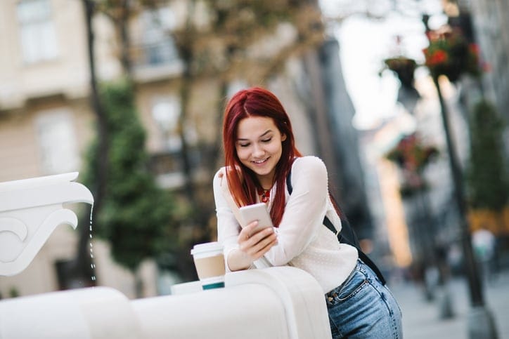 red haired woman smiling and texting
