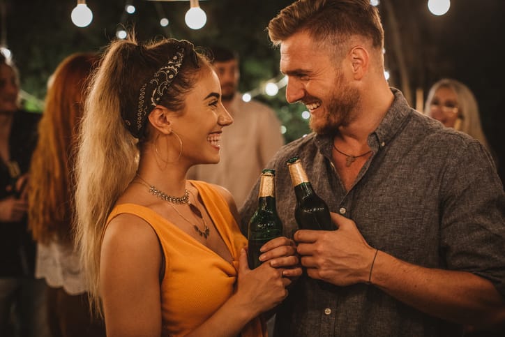 couple smiling with beers in hands