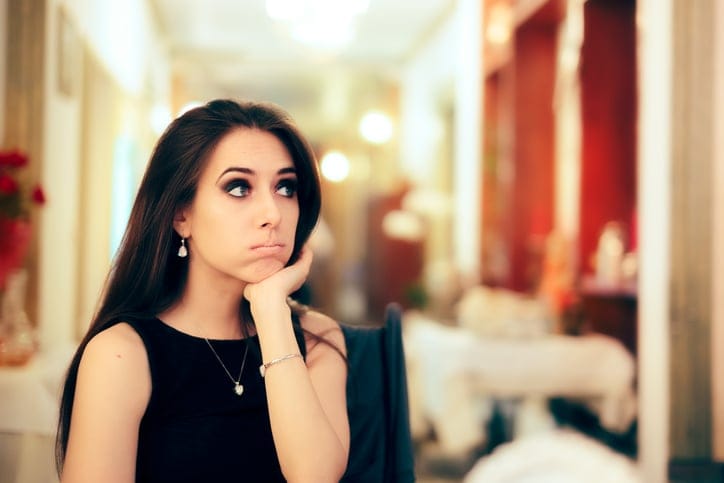 Woman standing alone looking bored.
