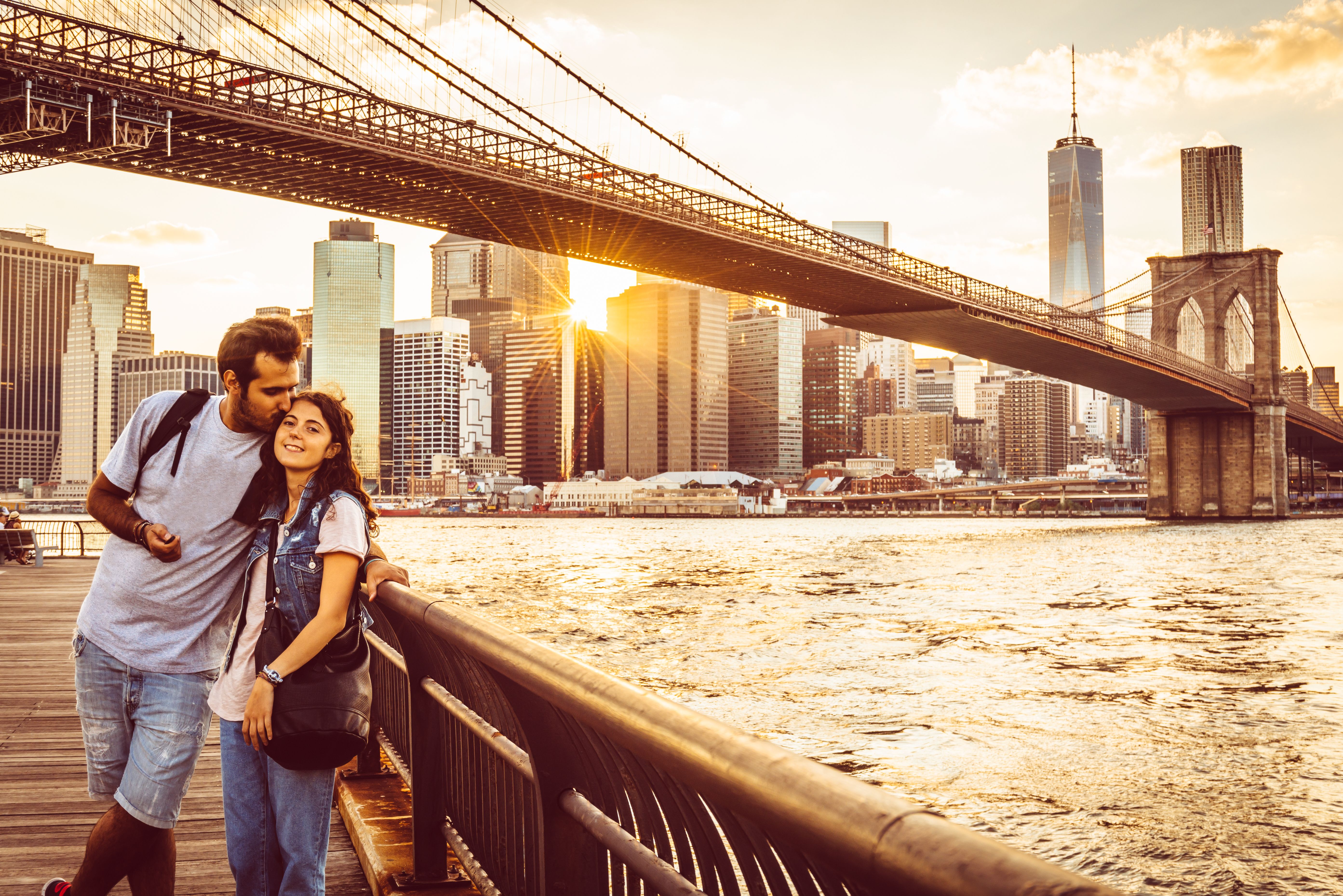 Young Couple Under Brooklyn Bridge at sunset.