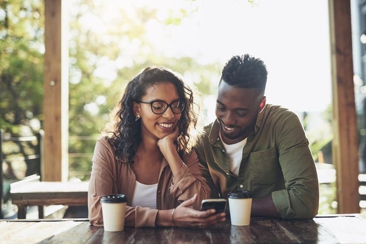 Shot of a woman using her cellphone while sitting in a cafe with her boyfriend