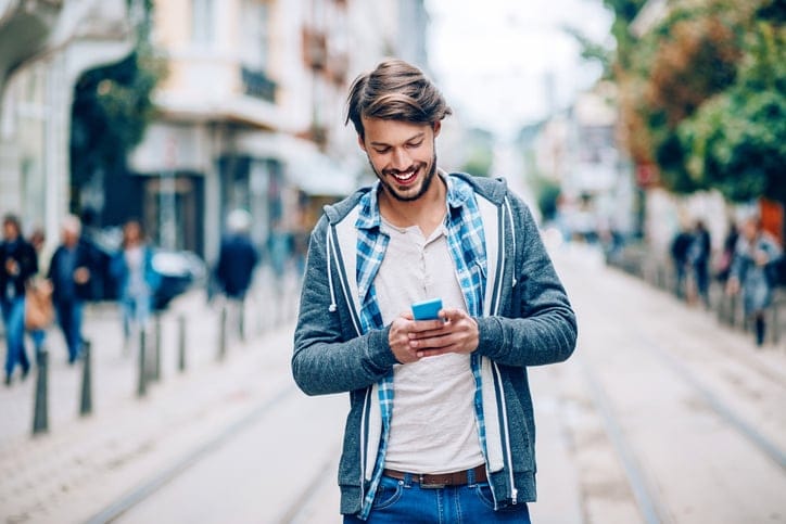 Happy man with smart phone text messaging