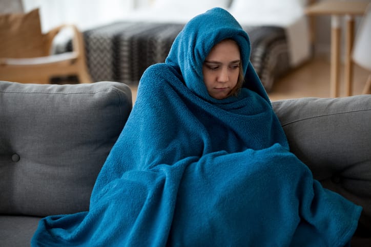 Woman wrapped in a blanket at home.