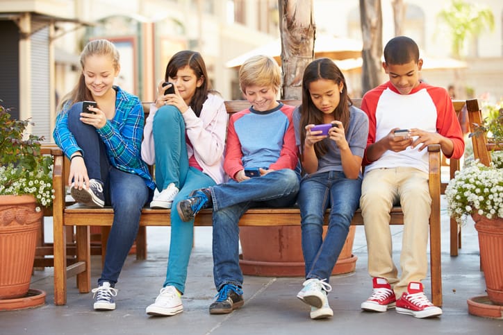 Group of children sitting on their phones.