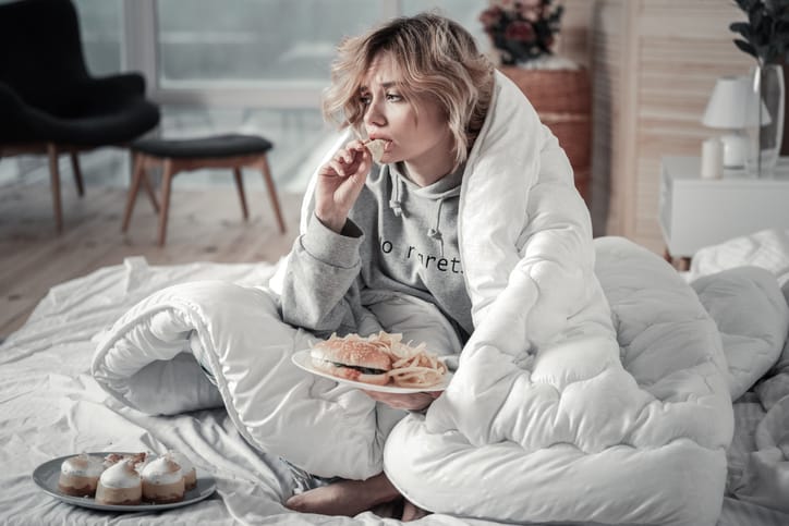 girl sitting in bed upset eating