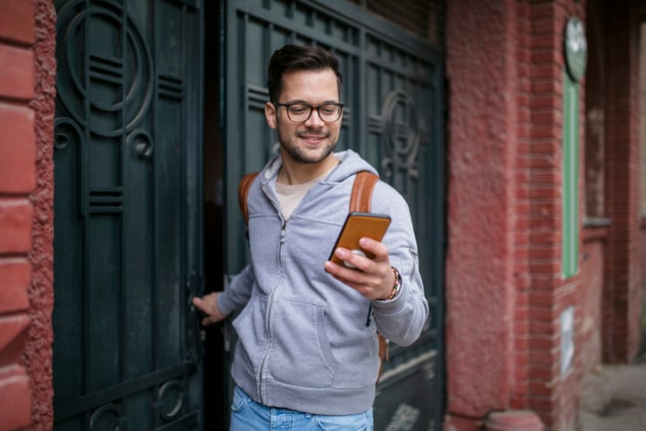 smiling guy texting leaving apartment