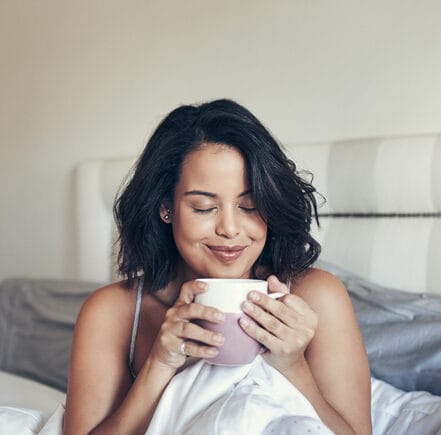 brunette woman in bed with coffee