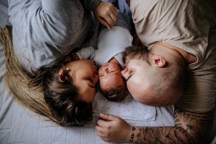 Family laying on bed enjoying day at home.