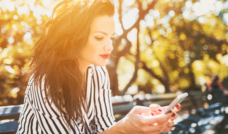 woman in sunset looking at smartphone