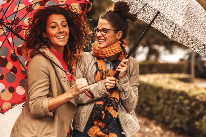 two friends holding umbrellas