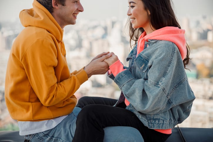 couple sitting on wall holding hands