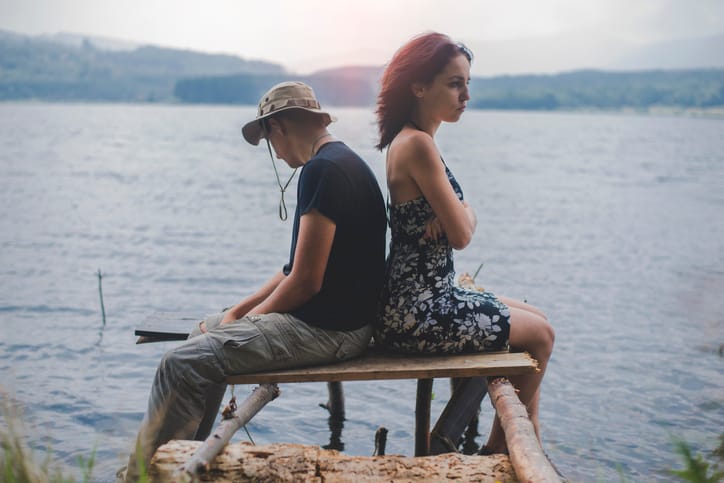 unhappy couple sitting near water