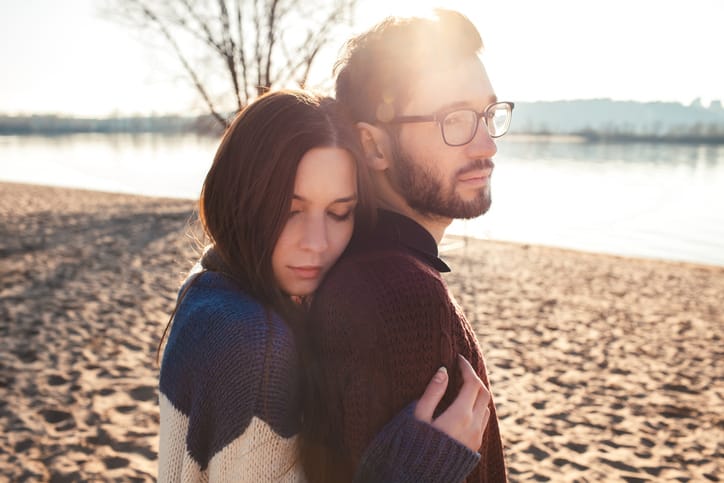 couple holding each other near water