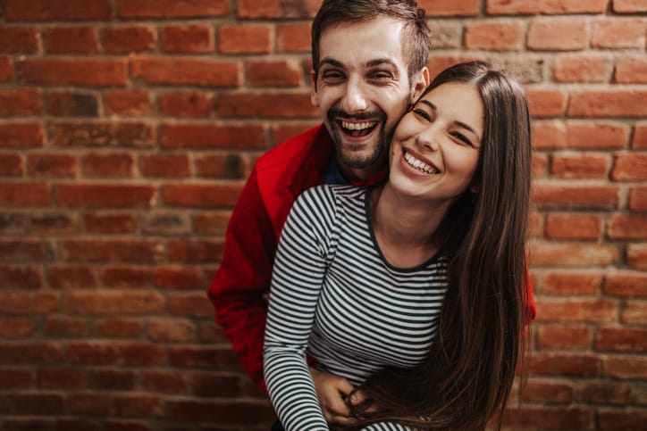 laughing couple beside wall