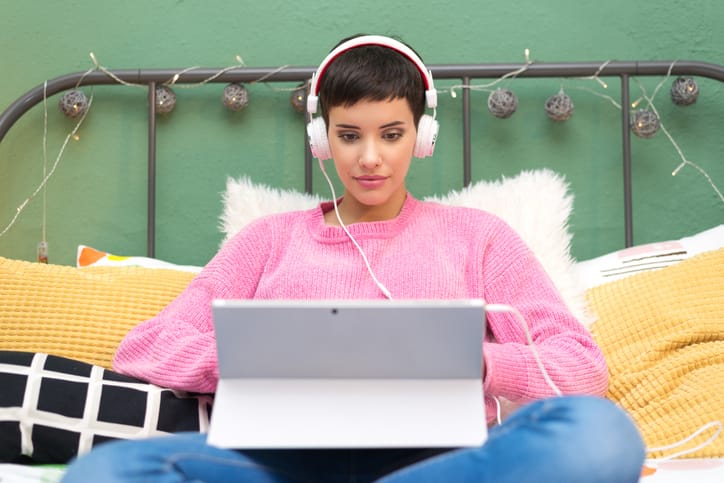 woman in pink sweater looking at laptop