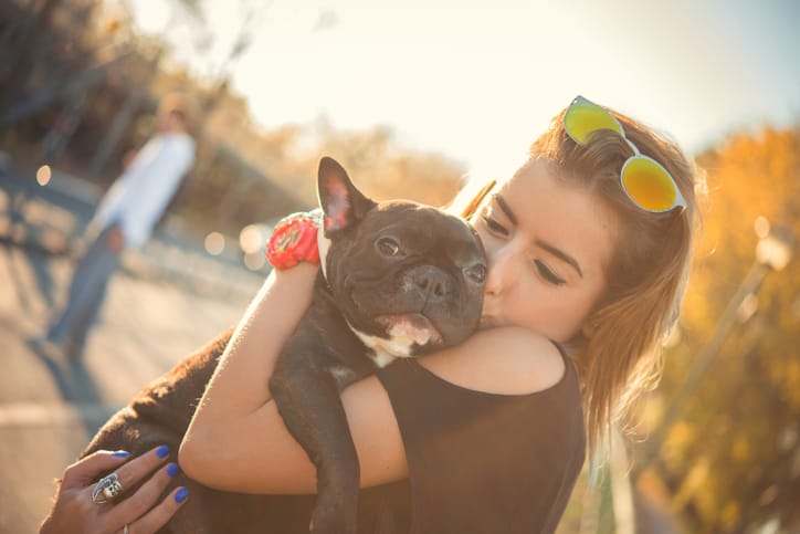 woman holding and kissing her dog