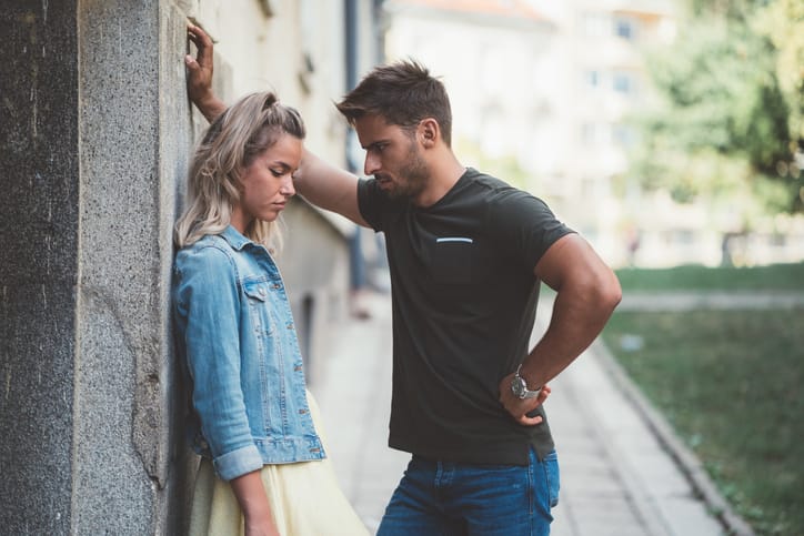 man leaning over woman against a wall