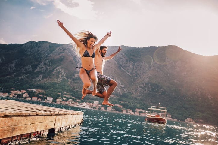 Young couple jumping from a pier into the water.