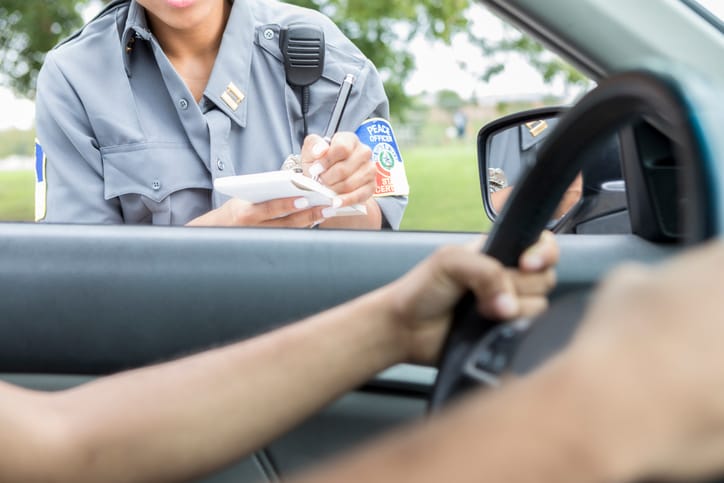 Police officer writing a ticket to a driver.