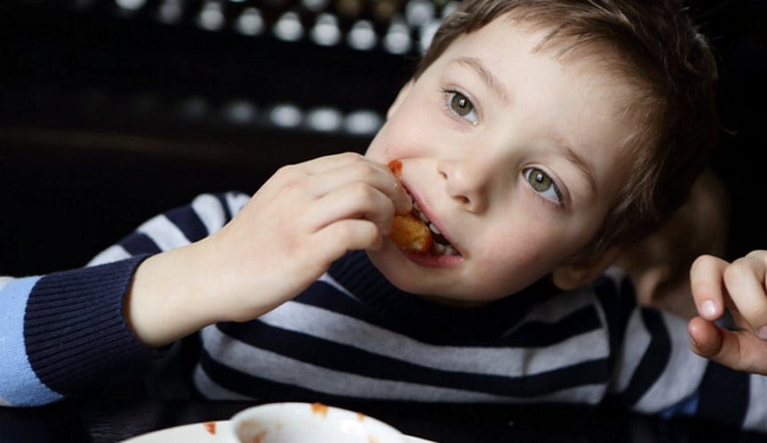 young boy eating chicken