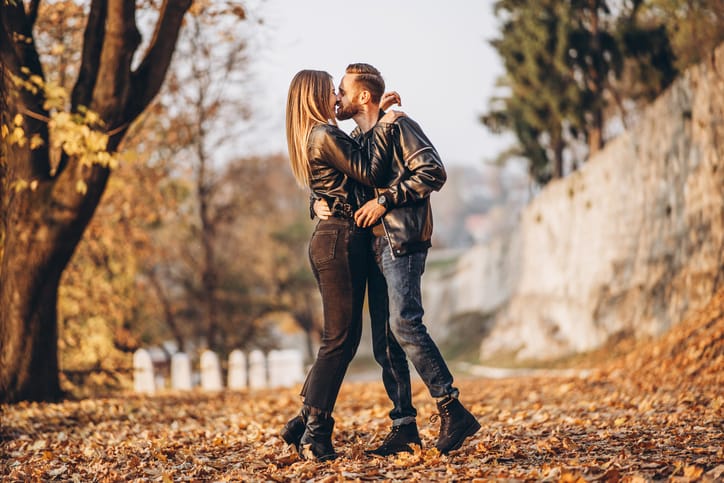 couple kissing in autumn leaves