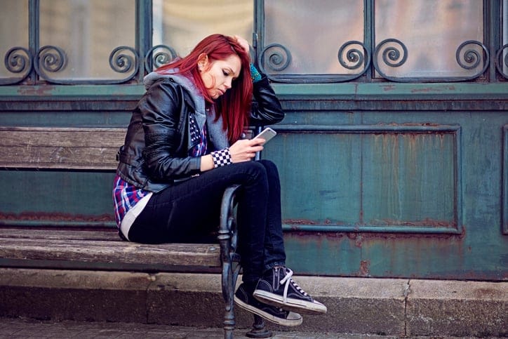 woman with red hair on steps texting