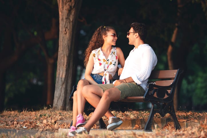 young couple sitting outside on a bench talking