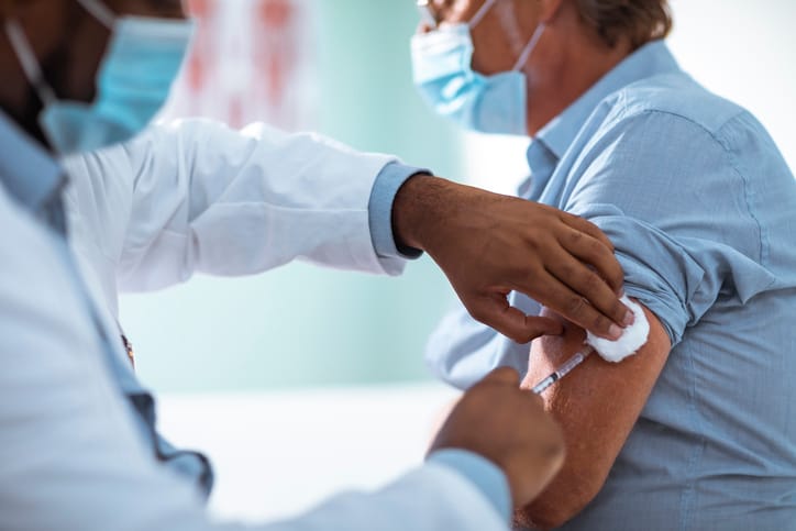 Mature man taking a vaccine from his doctor.