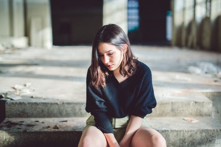 Sad woman sitting in bedroom.