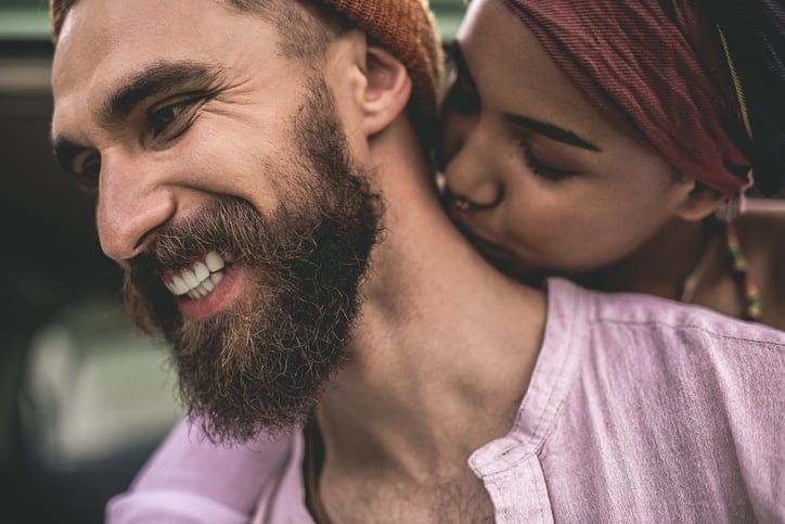Woman kissing her boyfriend's neck.