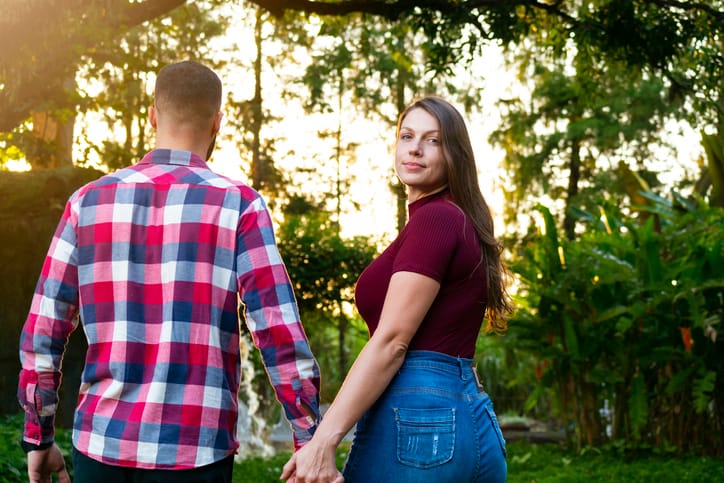 woman looking back while holding boyfriend's hand