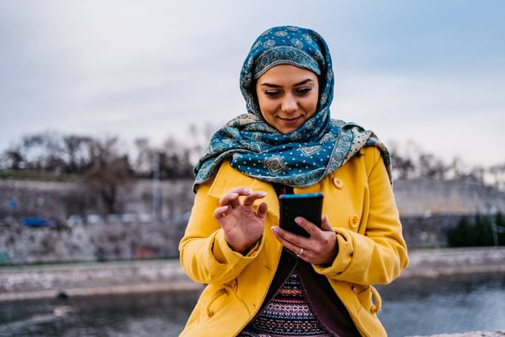 Young Muslim woman using phone.
