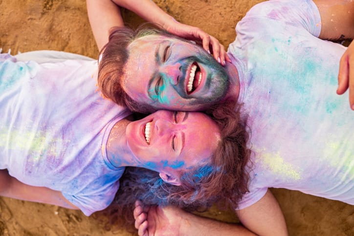 Couple laying on the floor covered in paint.