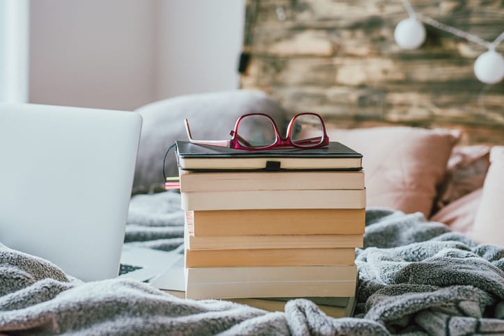 Stack of books on a bed.