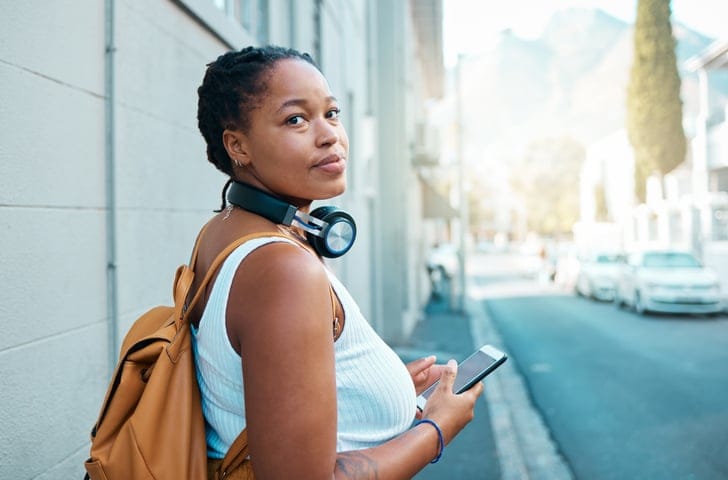 woman with headphones texting outside