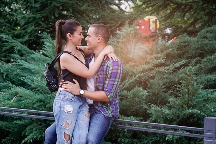 couple kissing outside greenery