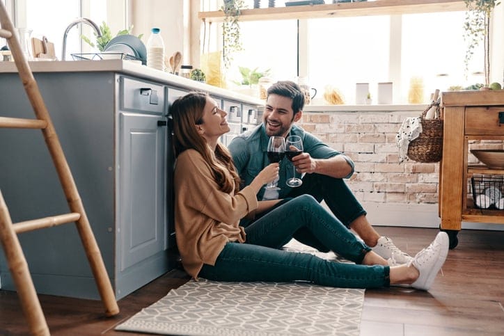 couple drinking wine in kitchen. Beautiful young couple drinking wine while sitting on the kitchen floor at home