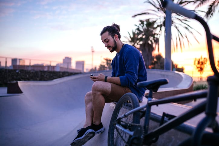 trendy guy texting at skate park