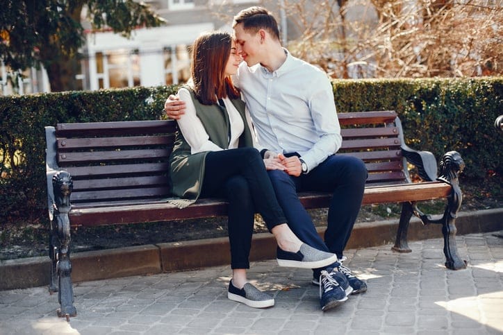 young couple sitting on a bench kissing