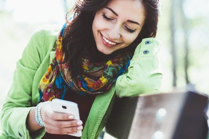 Young woman text messaging outside.