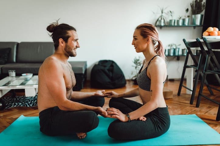 Young woman and man doing yoga at home.