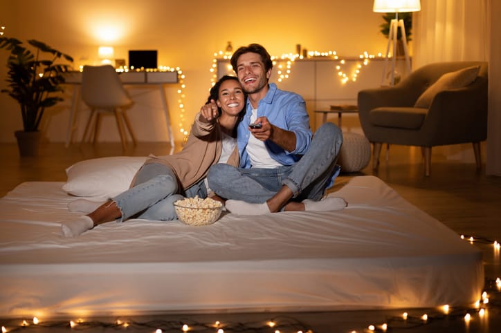Couple watching movie together, eating popcorn.