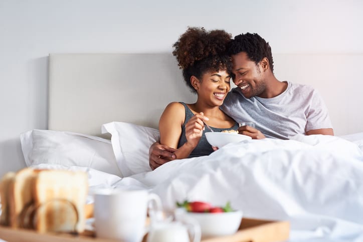 Happy young couple enjoying breakfast in bed.