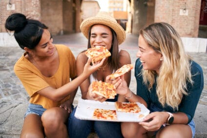 Happy girlfriends eating pizza.