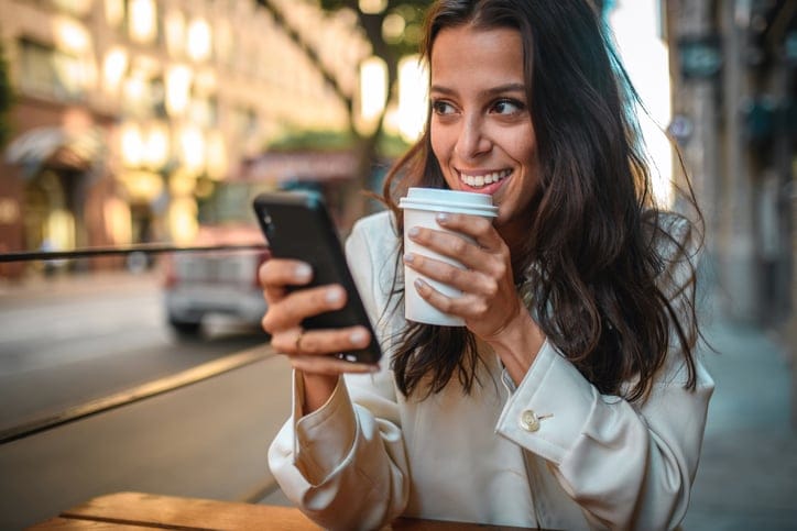 woman carrying phone and coffee