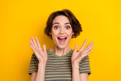 Woman smiling with her hands up shocked.