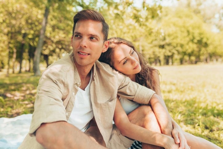 Couple sitting outside in trees.