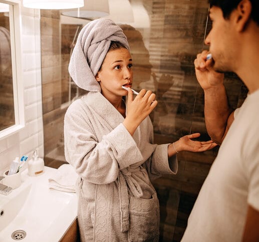 Couple brushing their teeth in the bathroom.