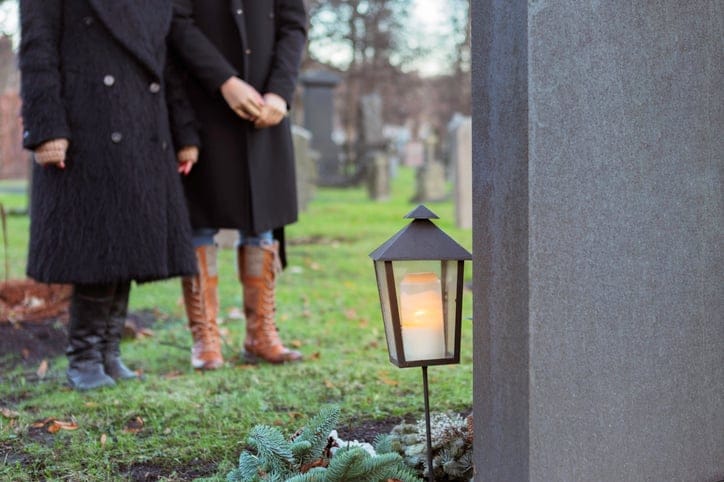 People standing at graveside.